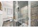 Walk-in shower featuring stone tile, glass doors, and built-in bench in renovated bathroom at 99 S Downing St # 605, Denver, CO 80209