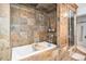 Luxurious bathroom featuring an oversized tub with wood accents and stone tile walls with shelves at 99 S Downing St # 605, Denver, CO 80209