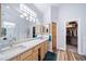 Bright bathroom featuring double sinks, a marble countertop, and a doorway leading into a closet at 2807 S Nelson St, Lakewood, CO 80227