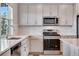 Well-lit kitchen featuring stainless appliances, white cabinets, quartz countertops, and a sink near the window at 24851 E 33Rd Dr, Aurora, CO 80019