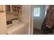 Functional laundry room with a white washer and dryer, shelving, and an open doorway at 12682 W Louisiana Ave, Lakewood, CO 80228