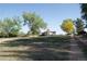 Backyard view with a brick chimney and back porch, surrounded by trees, grass, and clear blue sky at 6363 County Road 20, Longmont, CO 80504