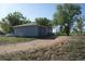 Garage and propane tank on a grassy, tree-lined lot with a long dirt driveway on a sunny day at 6363 County Road 20, Longmont, CO 80504