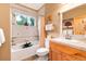 Well-lit bathroom with a shower over tub, neutral tiling, and wood vanity at 1300 W Caley Ave, Littleton, CO 80120