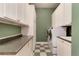 Laundry room with a green accent wall, checkered floors, washer, dryer and cabinets at 1300 W Caley Ave, Littleton, CO 80120