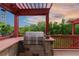 Outdoor kitchen featuring a built-in Lynx grill, stone accents, and pergola providing shade and style to the outdoor cooking space at 1300 W Caley Ave, Littleton, CO 80120