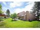 Backyard featuring lush green grass, mature trees, brick chimney, and a patio at 7414 S Monroe Ct, Centennial, CO 80122