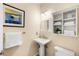 Well-lit bathroom with a pedestal sink, white cabinets, and modern fixtures at 9556 Kemper Dr, Lone Tree, CO 80124
