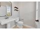 Elegant powder room with pedestal sink, floating shelves, and a classic toilet at 14959 Wistera Way, Broomfield, CO 80023