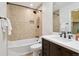 Classic bathroom with white sink, dark cabinets, and shower with tan tile surround at 2023 Mammoth Ct, Evergreen, CO 80439