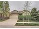 Lovely home with stone accents, dormer window, well-maintained landscaping, and a driveway leading to an attached garage at 17484 E 99Th Ave, Commerce City, CO 80022
