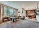 Bright living room with plush carpet, large windows, and an open floor plan leading to the dining and kitchen areas at 17484 E 99Th Ave, Commerce City, CO 80022