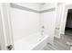 White bathtub with tiled wall and brushed nickel fixtures with adjacent door leading to bathroom at 3061 W 92Nd Ave # 2D, Westminster, CO 80031