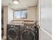 Modern laundry room features a front-load washer and dryer set, window with natural light, and neutral wall color at 3406 E Fair Pl, Centennial, CO 80121