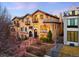 Exterior view of a multi-story home with stone and stucco accents, lush landscaping, and rod iron balconies at 566 Monroe St, Denver, CO 80206