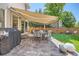 Backyard patio featuring a retractable awning, outdoor seating, stone pavers, grill and lush landscaping at 1382 Braewood Ave, Highlands Ranch, CO 80129