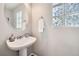 Cozy powder room with a pedestal sink, modern faucet, and glass block window at 1382 Braewood Ave, Highlands Ranch, CO 80129