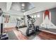 A finished exercise room with hardwood floors, elliptical machine, treadmill, weights, and custom ceiling and wall art at 3562 Pine Meadow Ave, Parker, CO 80138