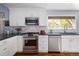 Bright kitchen featuring stainless steel appliances, white subway tile backsplash, and dark countertops at 10886 E Berry Ave, Englewood, CO 80111