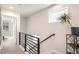 Hallway with metal railing leads to sunlit space, complemented by sleek shelving and a decorative plant at 3449 W 63Rd Pl, Denver, CO 80221