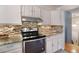 Kitchen with granite countertops, stainless steel oven, updated cabinetry, and tile backsplash at 12642 E Ohio Ave, Aurora, CO 80012