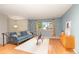 Bright living room featuring a blue velvet sofa, hardwood floors, and a large window with curtains at 12642 E Ohio Ave, Aurora, CO 80012