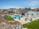 Lush backyard featuring a pool with a slide, a cozy fire pit area, and green artificial grass at 14712 Kalamath Ct, Westminster, CO 80023