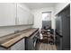 Well-lit laundry room with gray cabinets, rustic wood countertop, modern appliances, and additional shoe and storage racks at 14712 Kalamath Ct, Westminster, CO 80023
