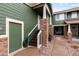 Exterior view of the green two-story home entrance, featuring brick accents and stairs to the front door at 19437 E Mann Creek Dr # A, Parker, CO 80134