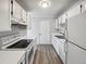 Galley kitchen featuring white cabinets and appliances with wood-look flooring at 9065 Cody Ct, Broomfield, CO 80021