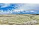 Aerial view of a large, grassy open area and distant treeline under a partly cloudy blue sky at 2188 Savage Rd, Elizabeth, CO 80107