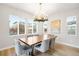 Elegant dining room with modern chandelier, large window with blinds and a spacious wooden table with seating for six at 10906 Pastel Pt, Parker, CO 80134