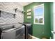 Charming laundry room featuring decorative wallpaper, green accent wall and washer and dryer at 10906 Pastel Pt, Parker, CO 80134