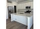 Modern kitchen with stainless steel appliances, white cabinets, an island with stone countertops, and wood flooring at 728 N Clubview St, Watkins, CO 80137