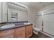 Well-lit bathroom featuring double sinks, wood cabinets, and a glass-enclosed shower for a spa-like experience at 21753 E Heritage Pkwy, Aurora, CO 80016