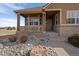 Close up of the home's front porch, with stone landscaping, brick veneer and a covered porch with seating at 21753 E Heritage Pkwy, Aurora, CO 80016
