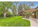 Expansive backyard featuring lush green grass, mature trees, and a covered patio for comfortable outdoor living at 2310 Squires Ct, Longmont, CO 80501