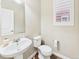 Cozy half bathroom with a pedestal sink, toilet, and a window with shutter, simple and functional at 9236 E 52Nd Dr, Denver, CO 80238