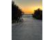 Long driveway with an iron gate offering scenic views of a distant sunset over the pastures at 970 Inyokern Ct, Watkins, CO 80137