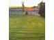 Spacious, manicured yard with a white fence, offering a serene view of the sunset in the distance at 970 Inyokern Ct, Watkins, CO 80137