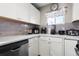 Corner of an efficient kitchen with stainless steel dishwasher and plenty of counter appliances and white cabinets at 6521 E 70Th Pl, Commerce City, CO 80022