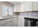 View of the kitchen sink with white cabinets, stainless steel dishwasher, and tile backsplash at 6521 E 70Th Pl, Commerce City, CO 80022