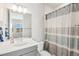 Bright bathroom featuring a single sink vanity with gray cabinets and a shower/tub combo with a striped shower curtain at 1526 Golden Sill Dr, Castle Pines, CO 80108