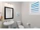 Cozy half bathroom with a pedestal sink, toilet, and a window with plantation shutters at 1526 Golden Sill Dr, Castle Pines, CO 80108