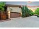 Two car garage with brown door and exterior number, lined with beautiful evergreens at 7444 E 9Th Ave, Denver, CO 80230