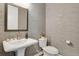 Stylish powder room with patterned wallpaper, a decorative mirror, and a pedestal sink, offering a touch of elegance at 1180 Ascent Trail Cir, Erie, CO 80516