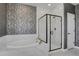 Modern bathroom featuring a luxurious soaking tub, a glass-enclosed shower with gold fixtures, and decorative wallpaper at 1180 Ascent Trail Cir, Erie, CO 80516