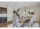 Dining area with a modern chandelier, spacious table, and a view towards the staircase and kitchen at 1180 Ascent Trail Cir, Erie, CO 80516