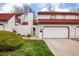 Townhome with a red tile roof, white stucco, an attached garage, and manicured lawn at 1321 Madero St, Broomfield, CO 80020