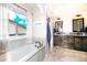 Bright bathroom with double sinks, wood cabinetry, and a soaking tub by the window at 605 Wild Honey Dr, Berthoud, CO 80513